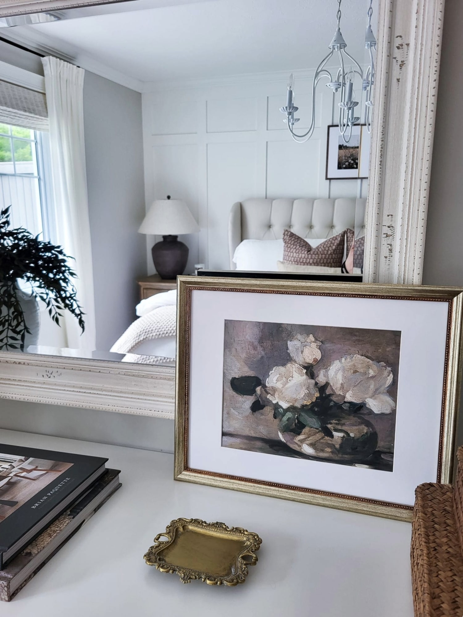 Antique-gold trinket dish styled on a bedroom dresser with framed floral art and books
